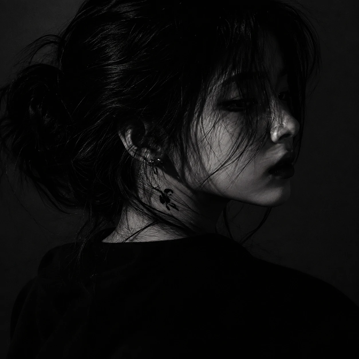 Monochrome dark aesthetic pfp girl framed in single-source side lighting.