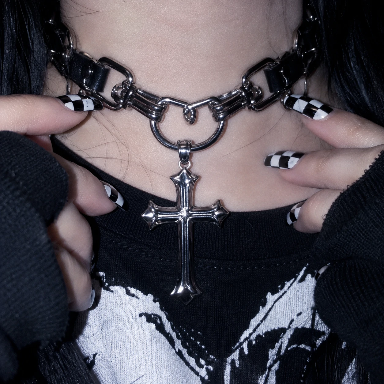 Y2K emo PFP close-up on black and white checkered nails holding a chunky cross choker